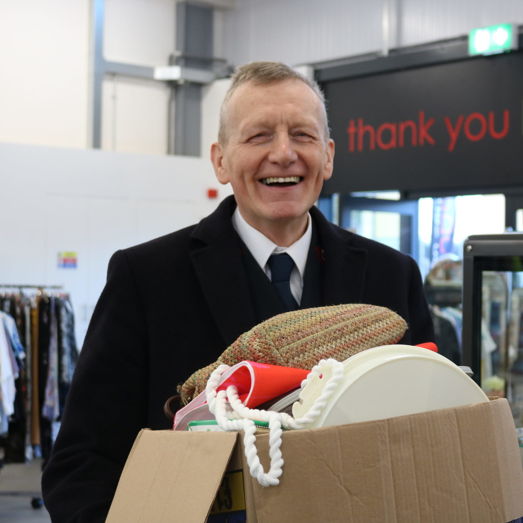 Man holding a box of items for donating, in a Salvation Army shop.