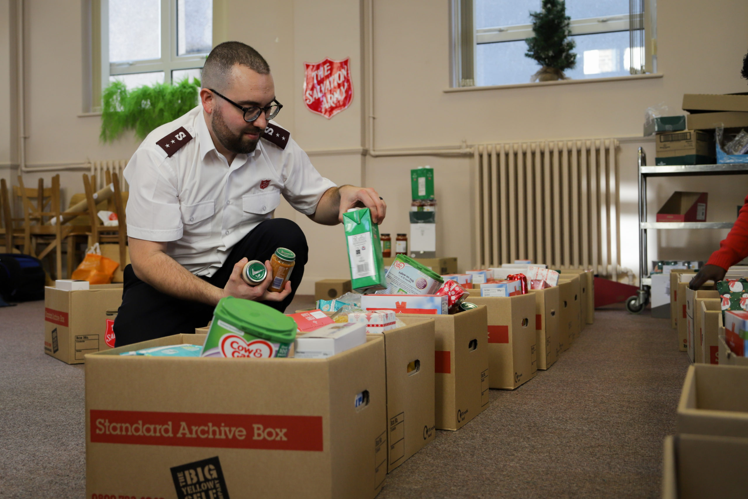 Salvationist putting food items in boxes for donations.