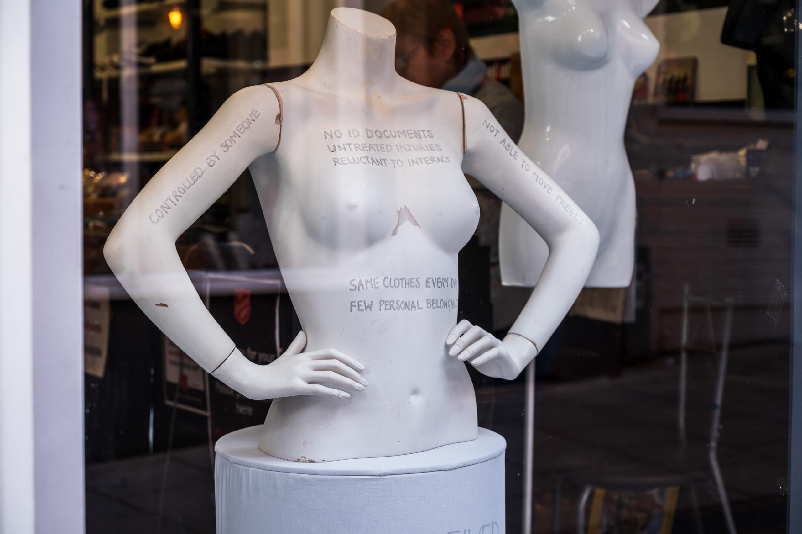 window display showing a naked mannequin with writing all over it