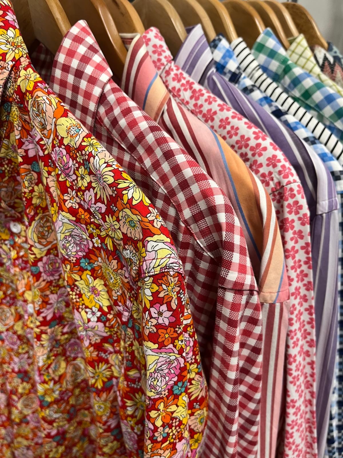 Colourful floral, checked and striped shirts on hangers