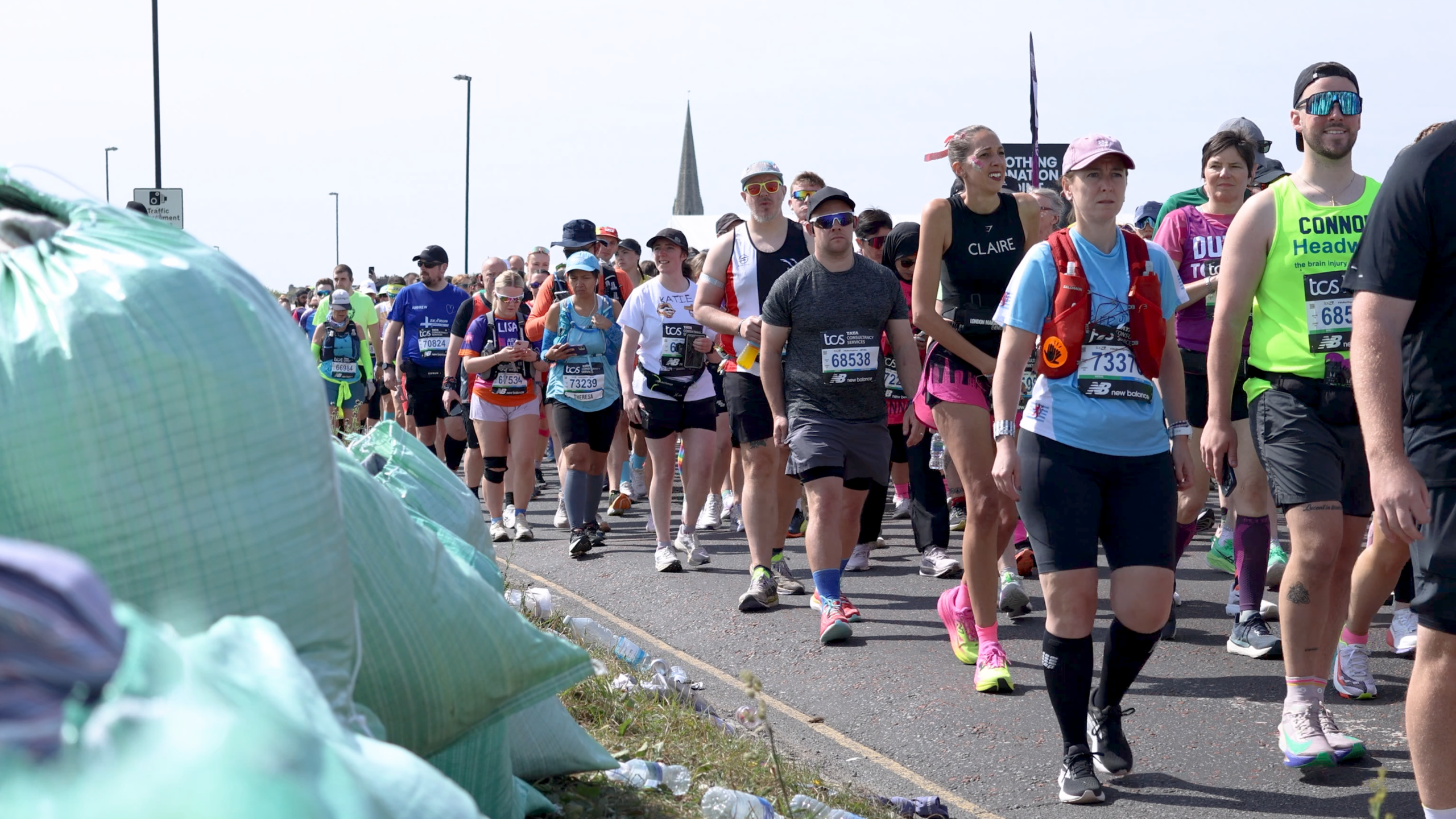 London marathon participants walking past bags filled with discarded clothing items.